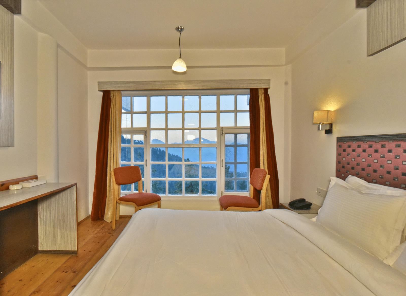 bedroom with large windows, showcasing natural light through open curtains at DLS Hillcrest Resort, Shimla